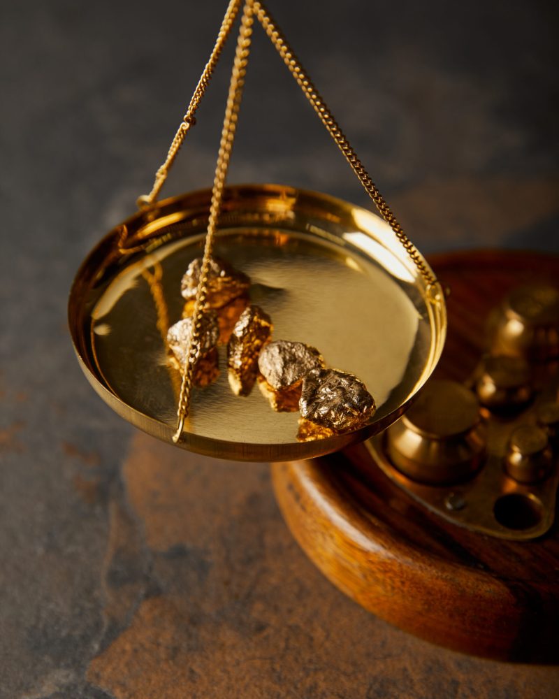 golden stones on scales on marble table